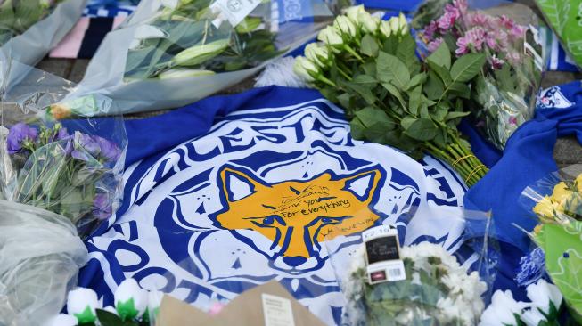 Sebuah bendera yang memperlihatkan logo Leicester City dengan pesan terima kasih terlihat ditumpukan bunga di luar Stadion King Power Stadium, Leicester, Inggris, Minggu (28/10). [AFP/Ben STANSALL]