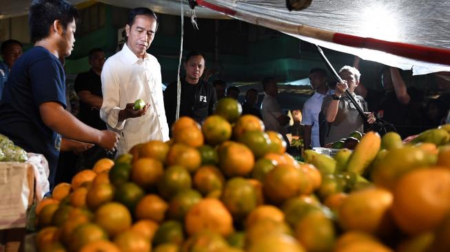 Presiden Joko Widodo membeli buah mangga ketika memantau kebutuhan bahan pokok di Pasar Surya Kencana, Bogor, Jawa Barat, Selasa (30/10). [ANTARA FOTO/Wahyu Putro] 