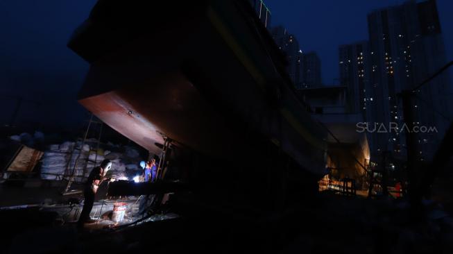 Sejumlah tukang memperbaiki kapal nelayan di Galangan Kapal Muara Angke, Jakarta, Selasa (6/11). [Suara.com/Muhaimin A Untung] 