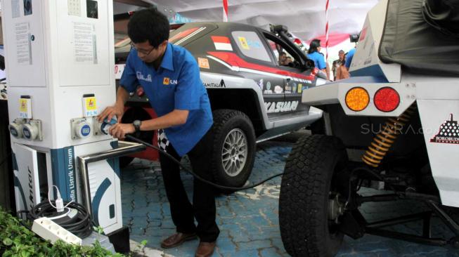 Teknisi saat mengisi daya mobil listrik saat uji coba di kantor PLN unit Induk industri PLN, Gambir, Jakarta, Jumat (9/11). (Suara.com/Fakhri Hermansyah)