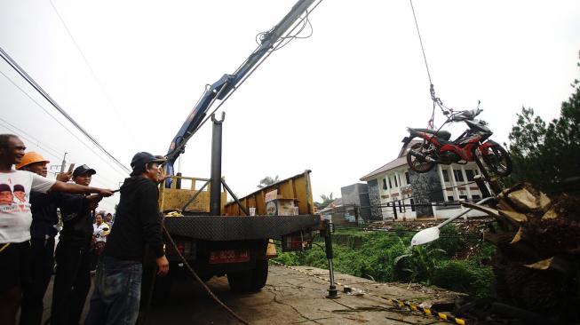 Petugas Dinas Lingkungan Hidup (DLHK) Pemkot Depok mengevakuasi sepeda motor yang terbawa longsor di sisi jalan Raya Citayam-Depok, Jawa Barat, Jumat (9/11). [ANTARA FOTO/Kahfie kamaru]