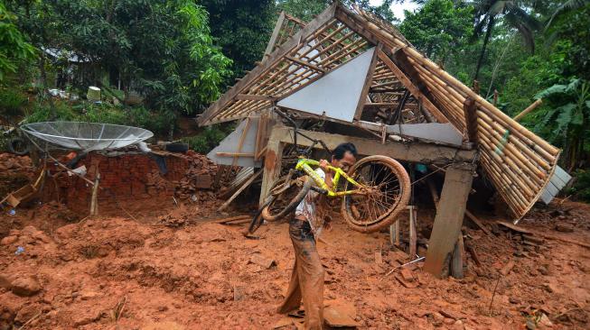 Warga membawa sepeda yang masih bisa diselamatkan di rumahnya yang tertimbun material tanah longsor di Desa Bojongsari, Kabupaten Tasikmalaya, Jawa Barat, Kamis (8/11). [ANTARA FOTO/Adeng Bustomi]