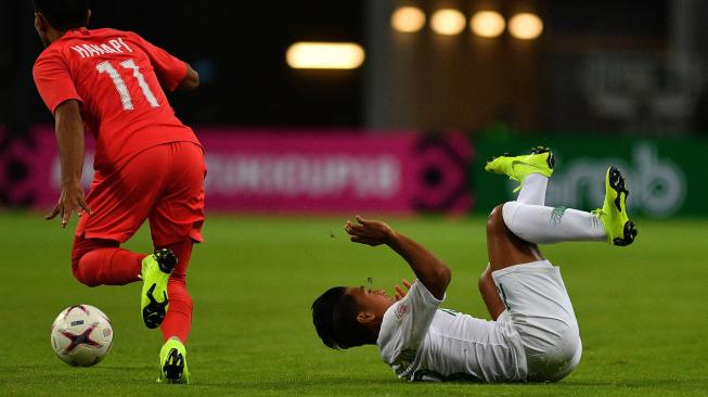 Pemain timnas Indonesia Febri Hariyadi (kanan) terjatuh usai berebut bola dengan pemain timnas Singapura Muhammad Yasir Hanapi dalam grub B Piala AFF 2018 antara Timnas Indonesia melawan Singapura di Stadion Nasional Singapura, Jumat (9/11). [ANTARA FOTO/Sigid Kurniawan]