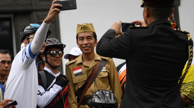 Presiden Joko Widodo (kanan) berfoto bersama warga seusai mengikuti kegiatan sepeda bersama dengan tema Bandung Lautan Sepeda di Bandung, Jawa Barat, Sabtu (10/11/2018). ANTARA FOTO/Wahyu Putro A