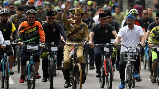 Presiden Joko Widodo (tengah) didampingi Gubernur Jawa Barat Ridwan Kamil (kanan) menyapa warga ketika mengikuti kegiatan sepeda bersama dengan tema Bandung Lautan Sepeda di Bandung, Jawa Barat, Sabtu (10/11/2018). ANTARA FOTO/Wahyu Putro A