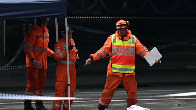 Personel Keadaan Darurat Negara (SES) meriksa sebuah mayat yang tergeletak di tempat insiden penusukan di Melbourne, Australia, Jumat (9/11). [AFP/William West]