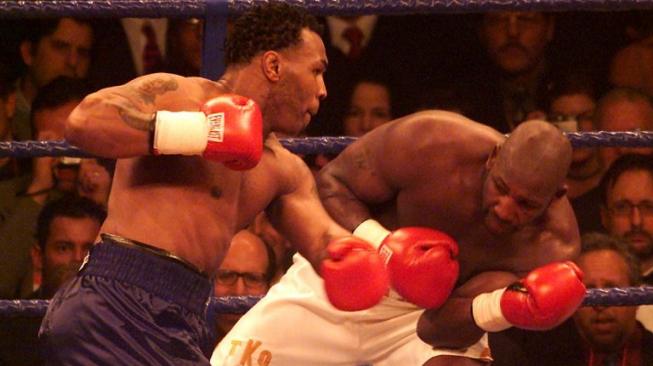 Legenda tinju dunia, Mike Tyson (kiri), melayangkan pukulan kiri ke arah penantangnya, Julius Francis, saat bertarung di Manchester Arena, Inggris, 29 Januari 2000. [AFP/Gerry Penny]