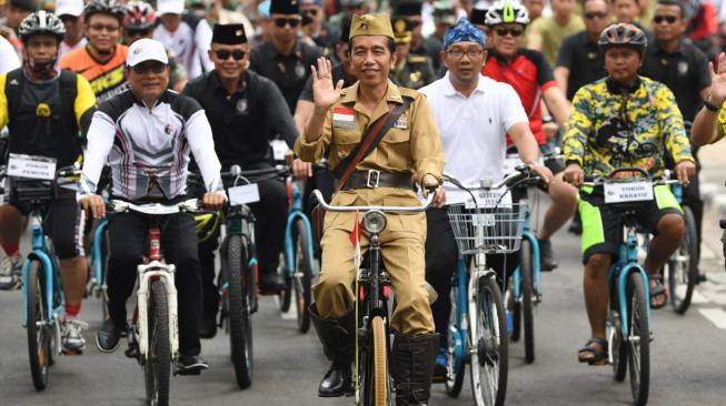 Presiden Joko Widodo mengenakan baju pejuang Bung Tomo (tengah) didampingi Kepala Staf Presiden Moeldoko (kiri) dan Gubernur Jawa Barat Ridwan Kamil (kedua kanan) menyapa warga ketika mengikuti kegiatan sepeda bersama dengan tema Bandung Lautan Sepeda di Bandung, Jawa Barat, Sabtu (10/11/2018). ANTARA FOTO/Wahyu Putro A