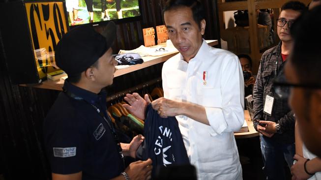 Calon Presiden Nomor Urut 01 Joko Widodo memamerkan kaos  sebelum berdiskusi dengan masyarakat kreatif Bandung di Simpul Space, Bandung, Jawa Barat, Sabtu (10/11). [ANTARA FOTO/Wahyu Putro]