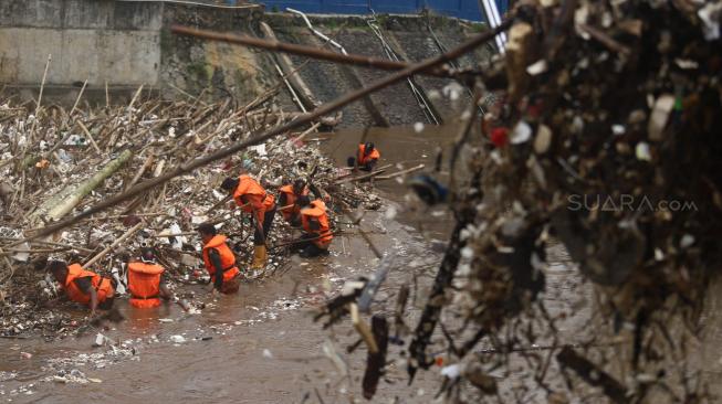 Petugas kebersihan DKI Jakarta membersihkan sampah di pintu air Manggarai, Jakarta Selatan, Senin (12/11). [Suara.com/Muhaimin A Untung] 