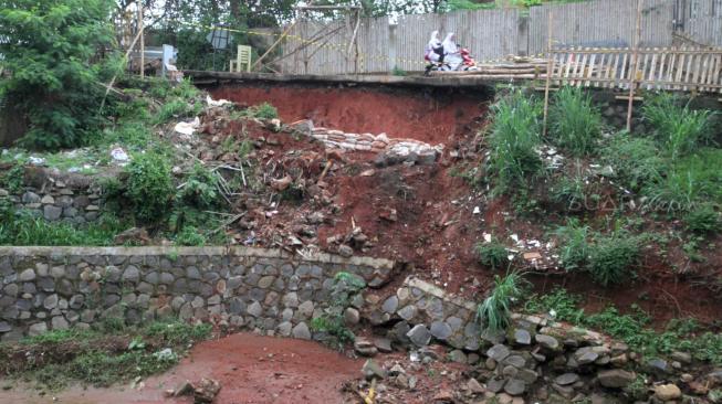 Suasana tanah longsor di Jalan Tiu yang berdekatan dengan pintu air sunter hulu daerah Setu Cipayung, Jakarta Timur, Senin (12/11). (Suara.com/Fakhri Hermansyah)