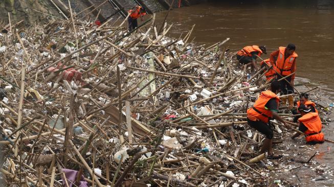 Petugas kebersihan DKI Jakarta membersihkan sampah di pintu air Manggarai, Jakarta Selatan, Senin (12/11). [Suara.com/Muhaimin A Untung] 