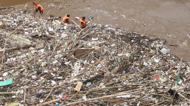 Petugas kebersihan DKI Jakarta membersihkan sampah di pintu air Manggarai, Jakarta Selatan, Senin (12/11). [Suara.com/Muhaimin A Untung] 