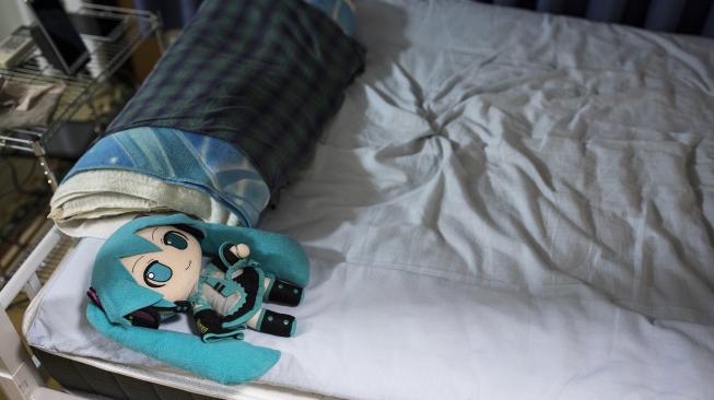 Boneka aktris virtual, Hatsune Miku mengenakan cincin kawin tergeletak di atas tempat tidur Akihiko Kondo di Tokyo, Jepang, Sabtu (10/11). (AFP/Behrouz MEHRI)