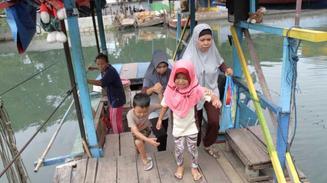 Warga menaiki perahu eretan yang ingin menyeberangi Kali Sunter di Rawa Badak, Jakarta Utara, Rabu (14/11).  (Suara.com/Fakhri Hermansyah)