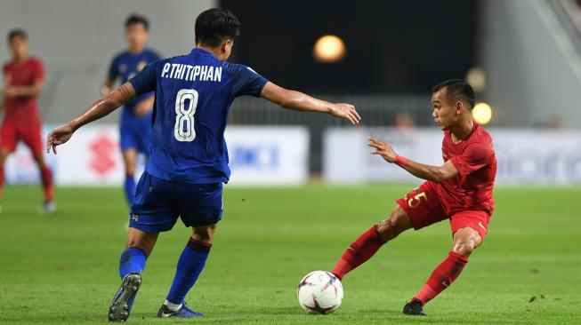 El futbolista indonesio Riko Simanjuntak (derecha) lucha por el balón con el futbolista tailandés Thitiphan Puangjan (izquierda) en el partido de seguimiento de la Copa AFF 2018 en el Estadio Nacional Rajamangala, Bangkok, Tailandia, el sábado (17/11/2018).  ENTRE FOTOS/Akbar Nugroho Gumay