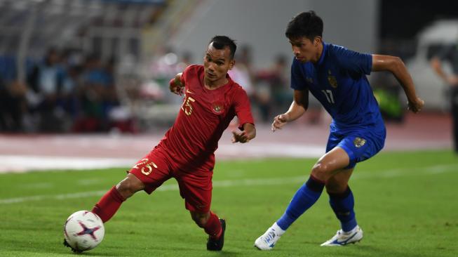 Pesepak bola Indonesia Riko Simanjuntak (kiri) berebut bola dengan pesepak bola Thailand Tanaboon Kesarat (kanan) dalam laga lanjutan Piala AFF 2018 di Stadion Nasional Rajamangala, Bangkok, Thailand, Sabtu (17/11). ANTARA FOTO/Akbar Nugroho Gumay