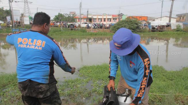 Pencarian barang bukti linggis yang digunakan tersangka kasus pembunuhan Haris Simamora di Aliran Kalimalang, Cikarang, Jawa Barat, Sabtu (17/11).(Suara.com/Fakhri Hermansyah)