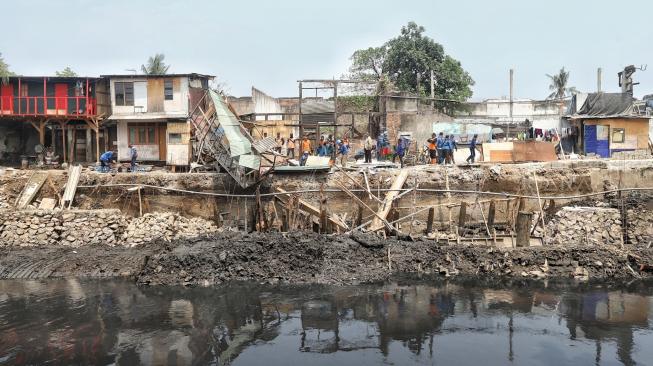 Sejumlah pekerja memperbaiki rumah yang rusak akibat terdampak longsor pada turap anak Kali Ciliwung di Jalan Kerapu, Ancol, Jakarta Utara, Rabu (21/11).[Suara.com/Muhaimin A Untung]