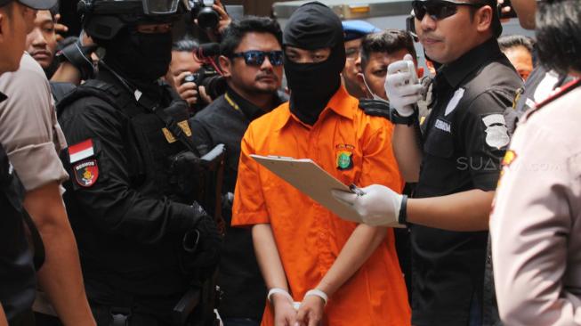 Tersangka Haris Simamora (tengah) saat  menjalani rekonstruksi pembunuhan satu keluarga di daerah Pondok Gede, Bekasi, Jawa Barat, Rabu (21/11). (Suara.com/Fakhri Hermansyah)