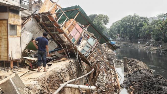 Sejumlah pekerja memperbaiki rumah yang rusak akibat terdampak longsor pada turap anak Kali Ciliwung di Jalan Kerapu, Ancol, Jakarta Utara, Rabu (21/11). [Suara.com/Muhaimin A Untung]