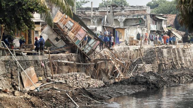 Sejumlah pekerja memperbaiki rumah yang rusak akibat terdampak longsor pada turap anak Kali Ciliwung di Jalan Kerapu, Ancol, Jakarta Utara, Rabu (21/11). [Suara.com/Muhaimin A Untung]