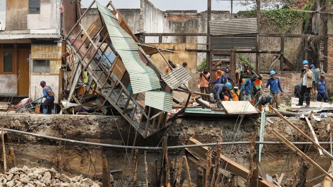 Sejumlah pekerja memperbaiki rumah yang rusak akibat terdampak longsor pada turap anak Kali Ciliwung di Jalan Kerapu, Ancol, Jakarta Utara, Rabu (21/11). [Suara.com/Muhaimin A Untung]