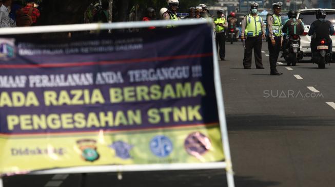 Petugas gabungan dari Badan Pajak dan Retribusi Daerah, Polisi Satuan Lalu Lintas Polda Metro, serta Jasa Raharja menggelar razia pajak di Jalan Kramat Raya, Jakarta Pusat, Kamis (22/11). [Suara.com/Muhaimin A Untung]
