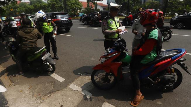 Petugas gabungan dari Badan Pajak dan Retribusi Daerah, Polisi Satuan Lalu Lintas Polda Metro, serta Jasa Raharja menggelar razia pajak di Jalan Kramat Raya, Jakarta Pusat, Kamis (22/11). [Suara.com/Muhaimin A Untung]
