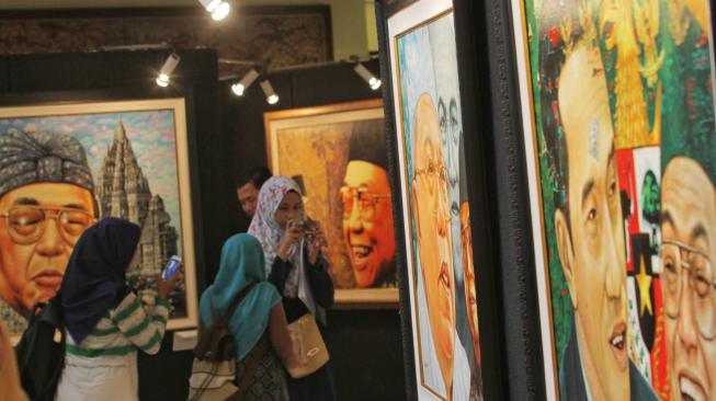 Pengunjung melihat pameran tunggal seni rupa Sang Maha Guru karya pelukis Nabila Dewi Gayatri di Senayan, Jakarta Pusat, Kamis (22/11).(Suara.com/Fakhri Hermansyah)