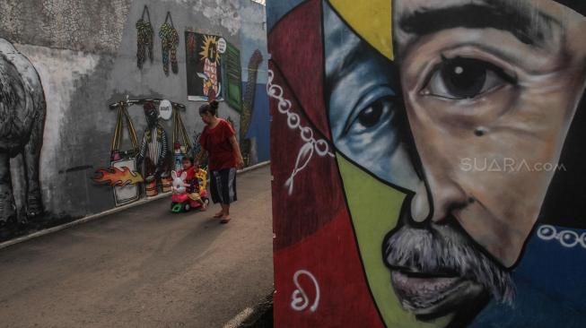 Warga melintas disamping mural 3D di tembok rumah warga daerah Jagakarsa, Jakarta Selatan, Minggu (25/11). (Suara.com/Fakhri Hermansyah)