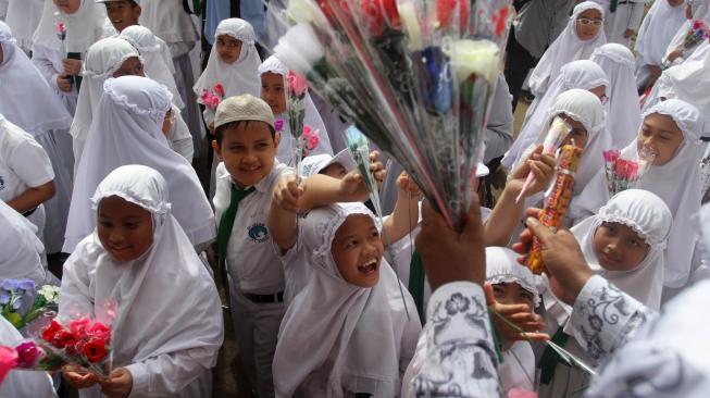 Sejumlah murid sekolah dasar memberikan bunga pada gurunya saat memperingati hari guru Nasional, di Sekolah Al Azhar, Padang, Sumatera Barat, Senin (26/11). ANTARA FOTO/Muhammad Arif Pribadi