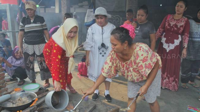 Ibu guru Rossi mengajarkan saat membantu ibu-ibu memasak untuk konsumsi acara di Sekolah  Kartini Kampung Lodan, Jakarta Utara, Senin (26/11). (Suara.com/Fakhri Hermansyah)