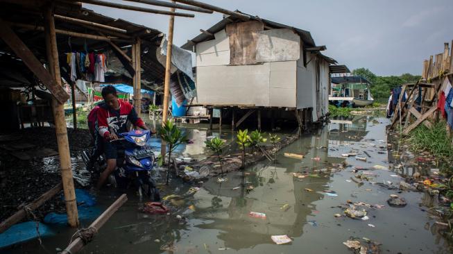 Warga melintasi banjir rob yang menggenang di Kampung Nelayan Muara Angke, Penjaringan, Jakarta, Senin (26/11). ANTARA FOTO/Aprillio Akbar