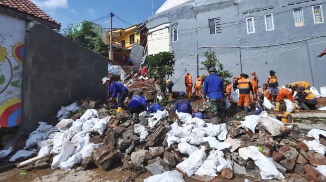 Pekerja mengevakuasi rumah yang rusak akibat longsor di Perumahan Pesona Kalisari IX, Pasar Rebo, Jakarta, Selasa (27/11). [Suara.com/Muhaimin A Untung]