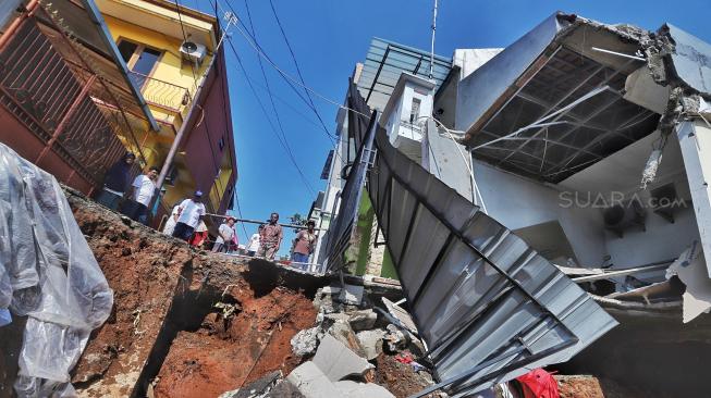 Warga melihat rumah yang rusak akibat longsor di Perumahan Pesona Kalisari IX, Pasar Rebo, Jakarta, Selasa (27/11). [Suara.com/Muhaimin A Untung]