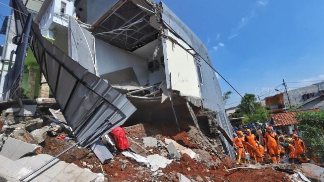 Pekerja mengevakuasi rumah yang rusak akibat longsor di Perumahan Pesona Kalisari IX, Pasar Rebo, Jakarta, Selasa (27/11). [Suara.com/Muhaimin A Untung]