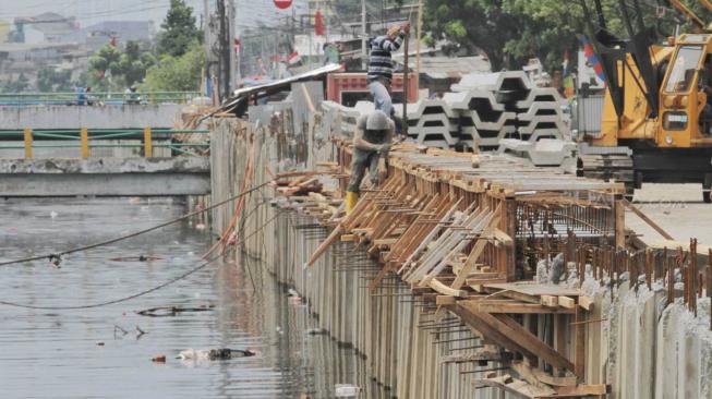 Pekerja menyelesaikan pemasangan dinding turap di kali Sention, Kemayoran, Jakarta pusat, Rabu (28/11). (Suara.com/Fakhri Hermansyah)