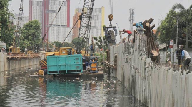 Pekerja menyelesaikan pemasangan dinding turap di kali Sention, Kemayoran, Jakarta pusat, Rabu (28/11). (Suara.com/Fakhri Hermansyah)