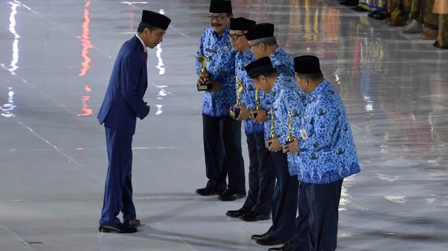 Presiden Joko Widodo (kiri) menyerahkan penghargaan KORPRI Award pada peringatan Hari Ulang Tahun Korps Pegawai Republik Indonesia (KORPRI) ke-47 di Istora Senayan, Jakarta, Kamis (29/11). ANTARA FOTO/Puspa Perwitasari