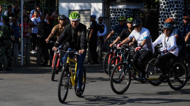 Presiden Joko Widodo (kiri) didampingi Menteri BUMN Rini Soemarno (kanan) dan Dirut BTN Maryono (kedua kanan) bersepeda menuju lokasi penyambungan instalasi listrik PLN gratis melalui sinergi BUMN untuk masyarakat di Bogor, Jawa Barat, Minggu (2/12/2018). ANTARA FOTO/Wahyu Putro A