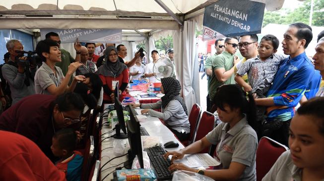 Presiden Joko Widodo (kiri) menggendong siswa penyandang disabilitas asal Sukabumi Mukhlis Abdul Holik disela Peringatan Hari Disabilitas Internasional Tahun 2018 di Bekasi, Jawa Barat, Senin (3/12). [ANTARA FOTO/Puspa Perwitasari]