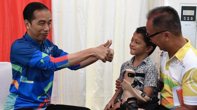 Presiden Joko Widodo (kiri) bersama Menteri Sosial Agus Gumiwang K berbincang dengan siswa penyandang disabilitas asal Sukabumi Mukhlis Abdul Holik (kedua kanan) disela Peringatan Hari Disabilitas Internasional Tahun 2018 di Bekasi, Jawa Barat, Senin (3/12/2018). [ANTARA FOTO/Puspa Perwitasari]