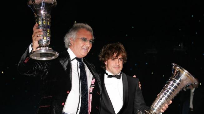 Fernando Alonso (kanan) memegang trofi juara dunia F1 2005, ditemani Flavio Briatore yang mewakili tim Renault selaku juara konstruktor. [AFP/Pascal Guyot]