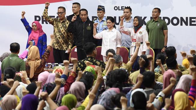 Presiden Joko Widodo (tengah) didampingi Ibu Negara Iriana Joko Widodo (keempat kanan) dan Menteri Sosial Agus Gumiwang Kartasasmita (kedua kiri) bernyanyi bersama penerima dan pendamping Program Keluarga Harapan (PKH) di Gelanggang Remaja Jakarta Timur, Jakarta, Senin (3/12). [ANTARA FOTO/Puspa Perwitasari]
