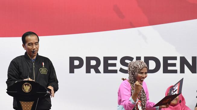 Presiden Joko Widodo (kiri) memberikan foto kepada penerima kartu Program Keluarga Harapan (PKH) saat sosialisasi di Gelanggang Remaja Jakarta Timur, Jakarta, Senin (3/12). [ANTARA FOTO/Puspa Perwitasari]