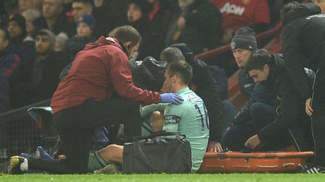 Centre-back Arsenal, Rob Holding (tengah) mendapat perawatan setelah mengalami cedera lutut di laga lanjutan Liga Inggris 2018/2019 kontra Manchester United di Old Trafford, Kamis (6/12/2018) dini hari WIB. [Oli SCARFF / AFP]