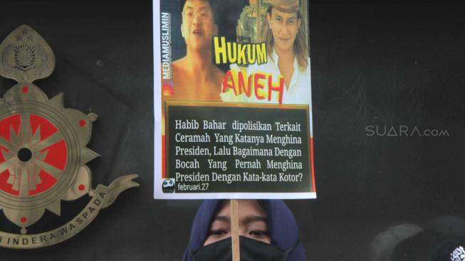 Massa yang tergabung dalam Laskar Pembela Islam (LPI) membawa poster tuntutan saat aksi mengawal pemeriksaan Habib Bahar bin Smith di depan Gedung Bareskrim, Gambir, Jakarta Pusat, Kamis (6/12). [Suara.com/Fakhri Hermansyah]