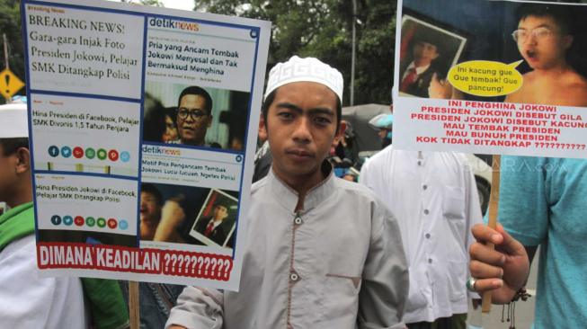 Massa yang tergabung dalam Laskar Pembela Islam (LPI) membawa poster tuntutan saat aksi mengawal pemeriksaan Habib Bahar bin Smith di depan Gedung Bareskrim, Gambir, Jakarta Pusat, Kamis (6/12). [Suara.com/Fakhri Hermansyah]