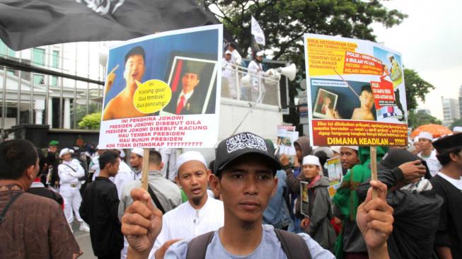 Massa yang tergabung dalam Laskar Pembela Islam (LPI) membawa poster tuntutan saat aksi mengawal pemeriksaan Habib Bahar bin Smith di depan Gedung Bareskrim, Gambir, Jakarta Pusat, Kamis (6/12). [Suara.com/Fakhri Hermansyah]